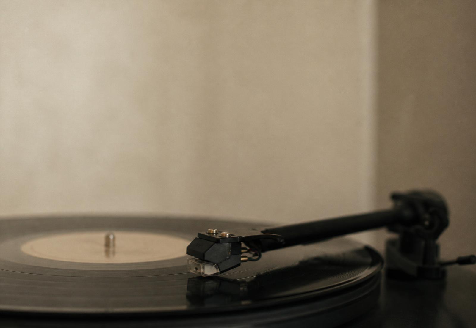 Braço de um toca-discos apoiado sobre um disco de vinil girando